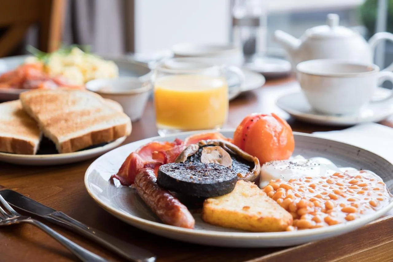 A plate of full English breakfast food on a wooden table at Judge's Lodging in York