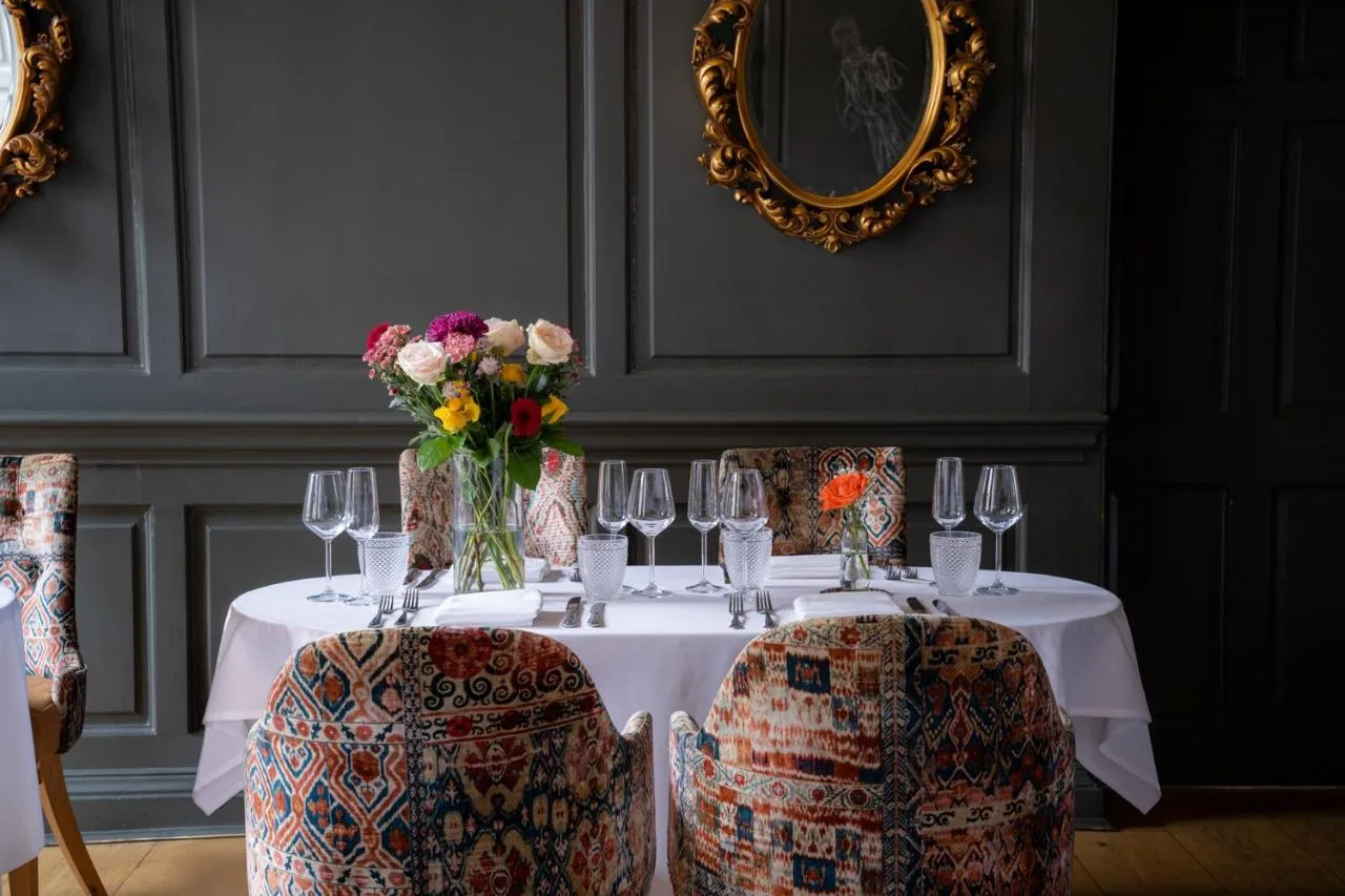 A table set with wine glasses and a vase of flowers at Judge's Lodging in York