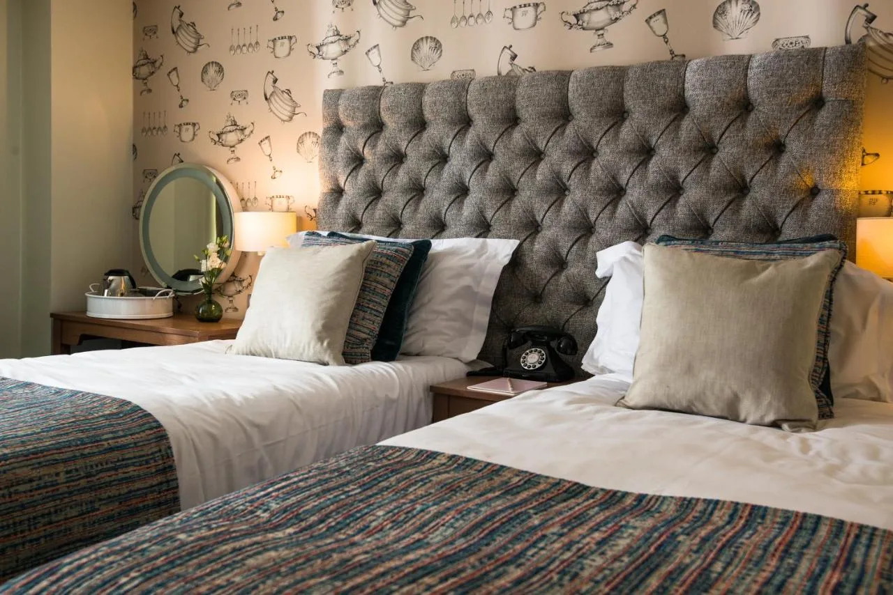 A bedroom with two beds and a large headboard at Judge's Lodging in York
